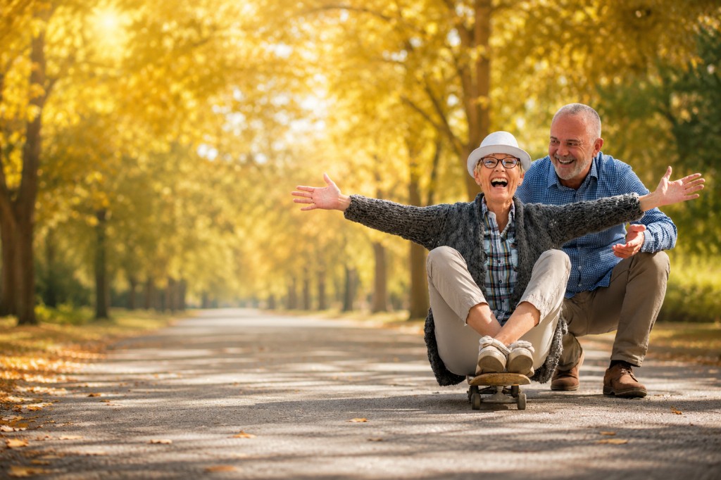 Joyful senior couple laughing together on a tree-lined autumn path
